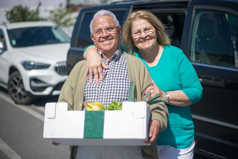 senior couple carrying a box of groceries